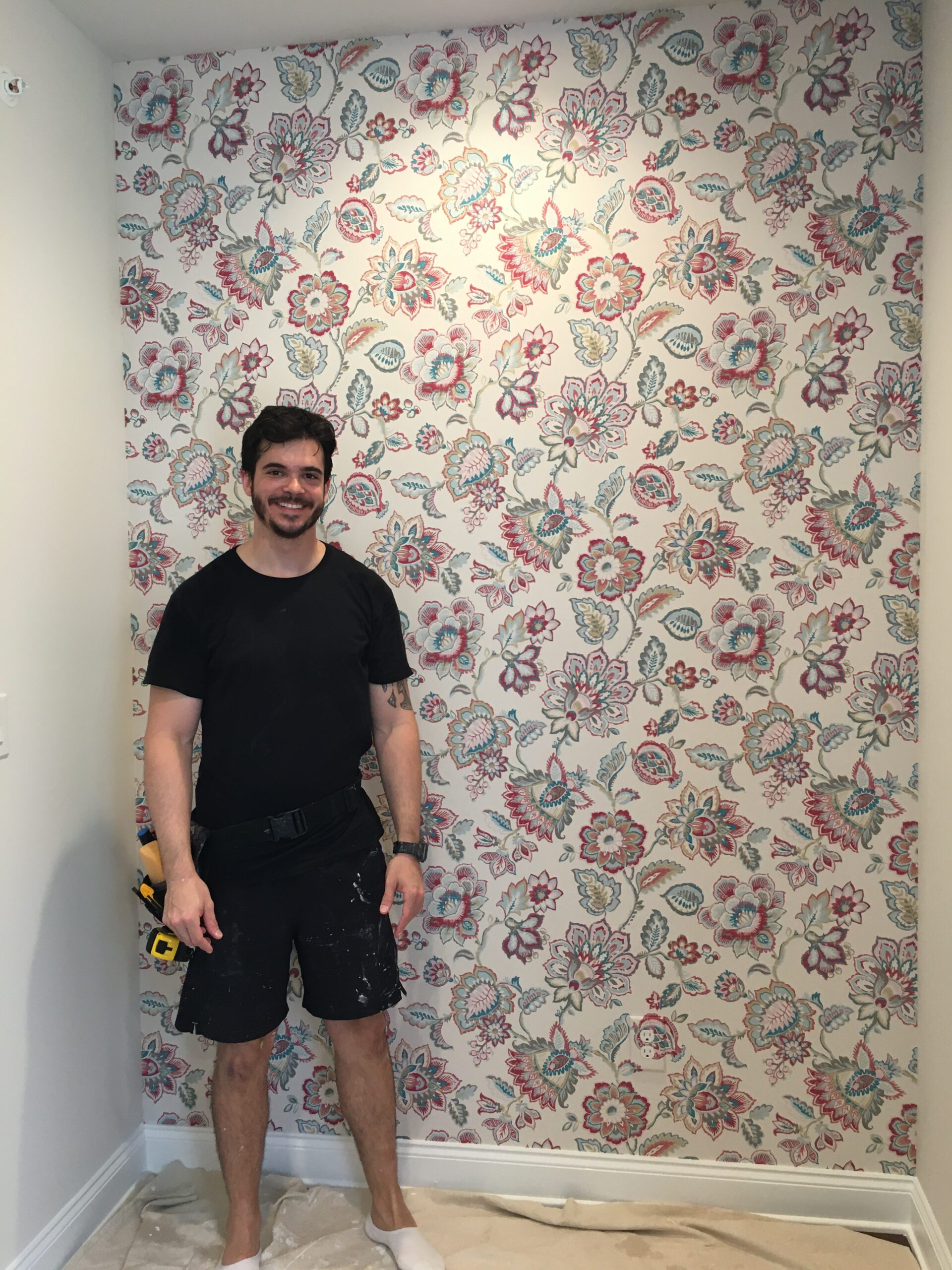 Professional wallpaper installer smiling proudly in front of a completed Jacobean floral wallpaper installation, Costa Blanca Spain