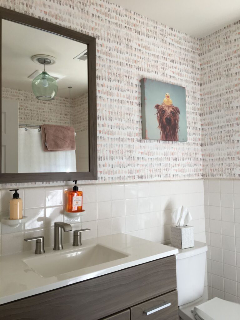 Professional wallpaper installation with a white and blush pink watercolour brushstroke pattern above white ceramic wall tiles in a modern bathroom, Costa Blanca Spain
