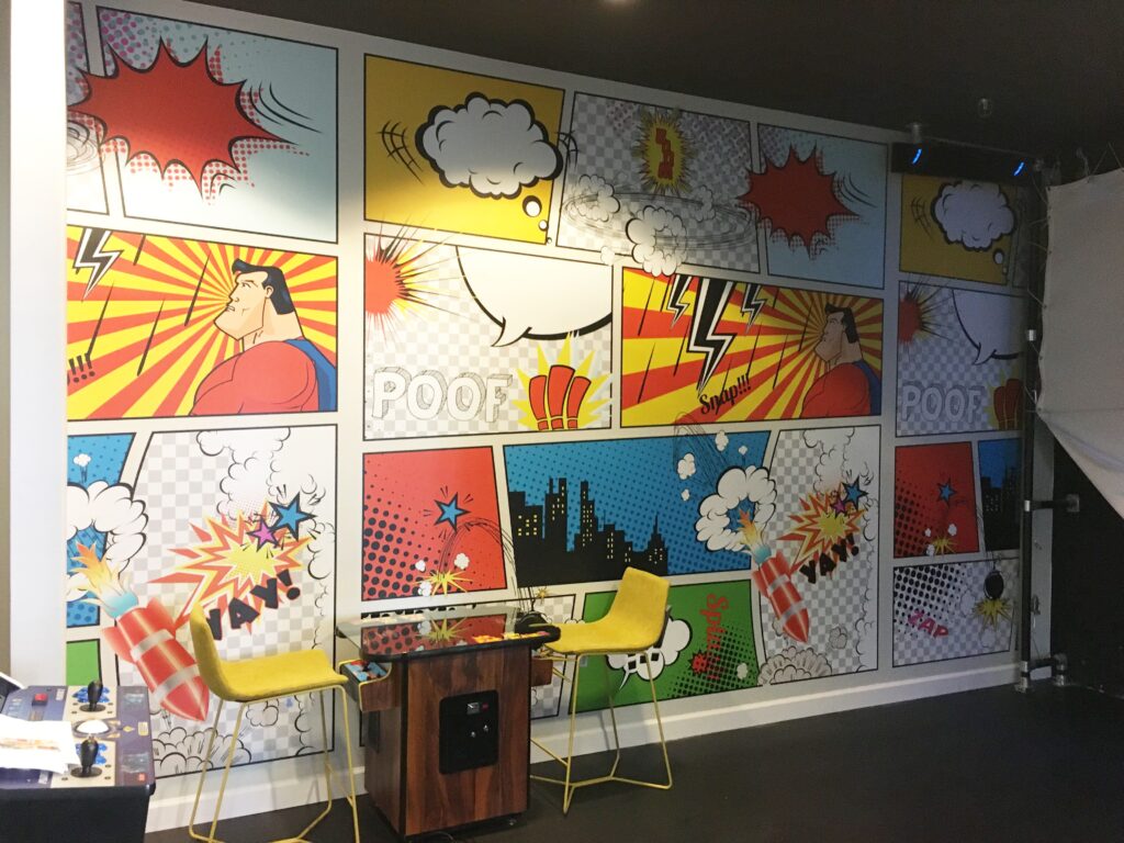 Professional large scale pop art comic book superhero mural wallpaper installation covering a full wall in bold primary colours in a games room, Costa Blanca Spain