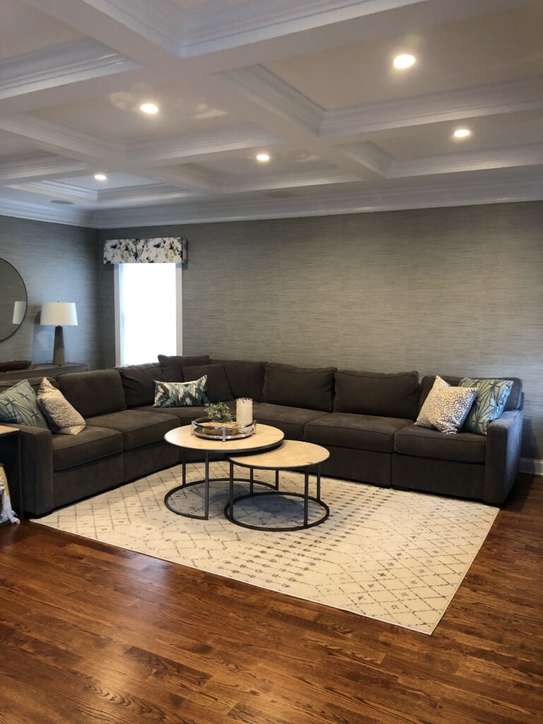 Professional grasscloth wallpaper installation covering full walls in a luxury living room with coffered ceiling, sage green natural texture, Costa Blanca Spain