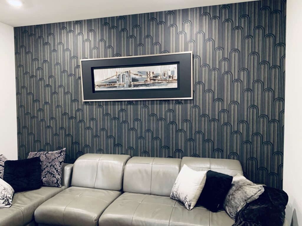 Professional feature wall wallpaper installation with a dark charcoal Art Deco arch pattern in a modern living room, Costa Blanca Spain