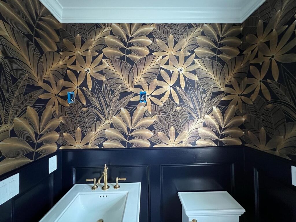 Professional wallpaper installation in a powder room featuring a dark navy and gold botanical leaf pattern, Costa Blanca Spain