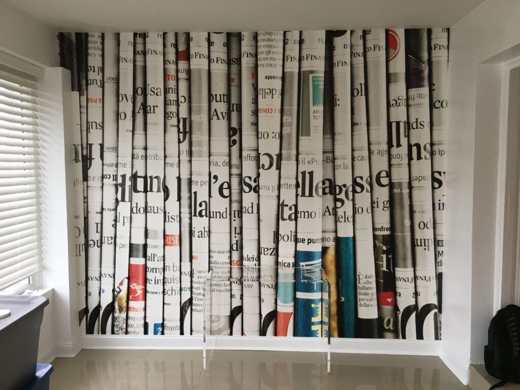 Professional large scale newspaper print photo mural wallpaper installation covering a full feature wall in black white and colour in a modern room, Costa Blanca Spain