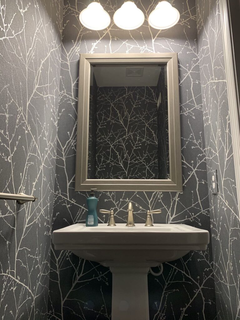Professional full room wallpaper installation with a dark charcoal and silver metallic bare branch tree pattern covering all walls of a powder room, Costa Blanca Spain