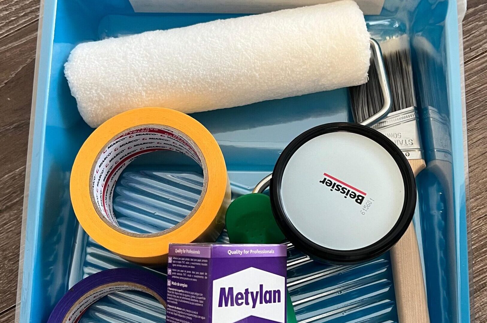 Wallpaper installation tools, including a paint tray, paint brush, masking tape, and Metylan Special wallpaper adhesive.